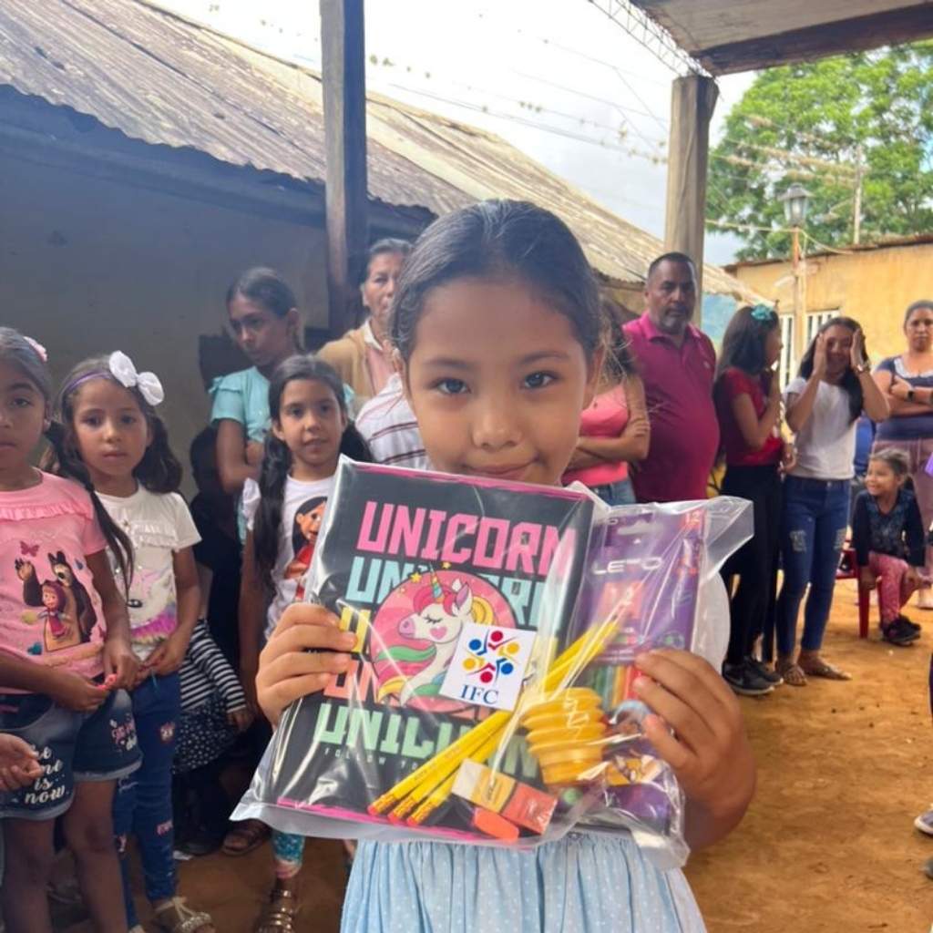 niña con cuadernos y grupo de niños detras