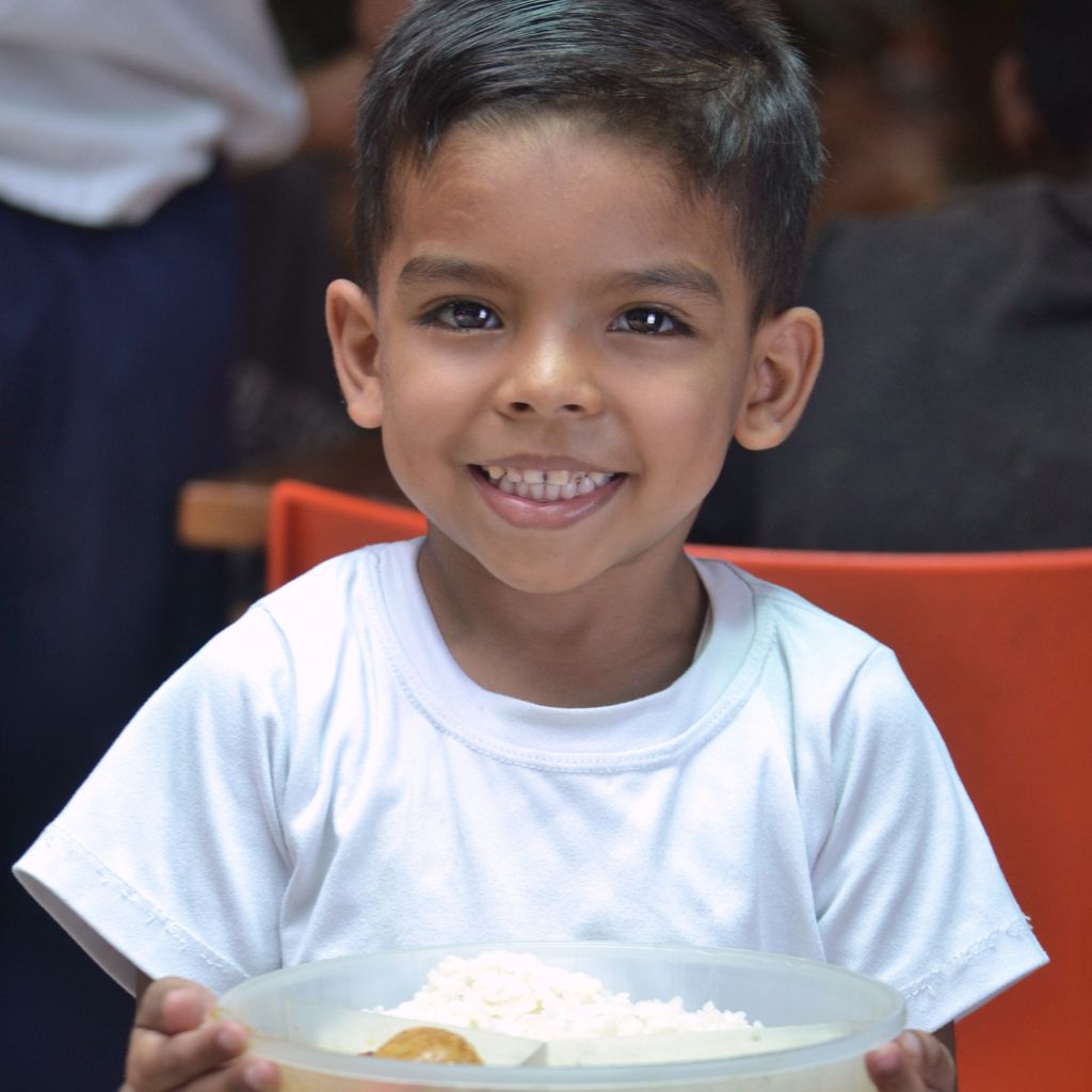 niño con plato de comida mira a la cámara