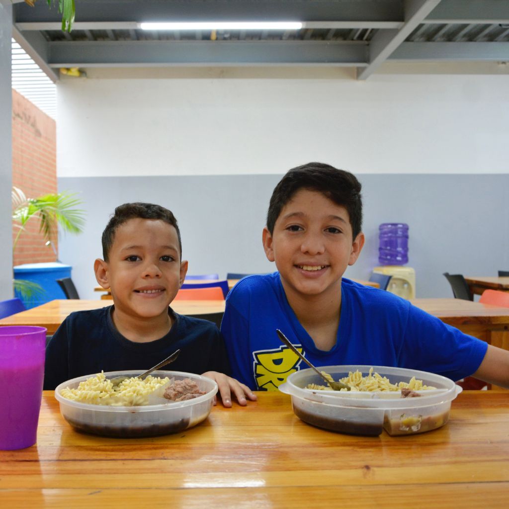 dos niños sonriendo con platos de comida