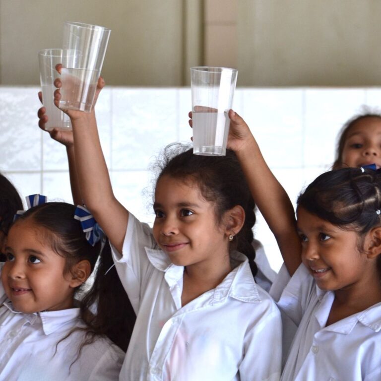 niñas alzan vaso de agua