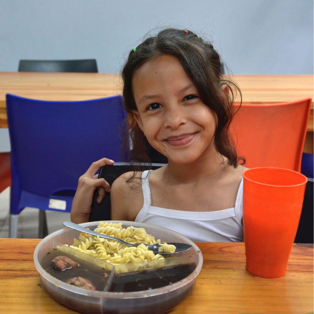 niña sonríe frente a plato de comida