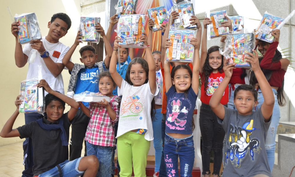 niños alzan sus kits escolares