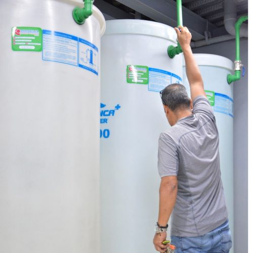tanques de agua y hombre revisando tubería