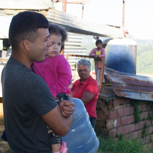 hombre con niña y botellón de agua vacío